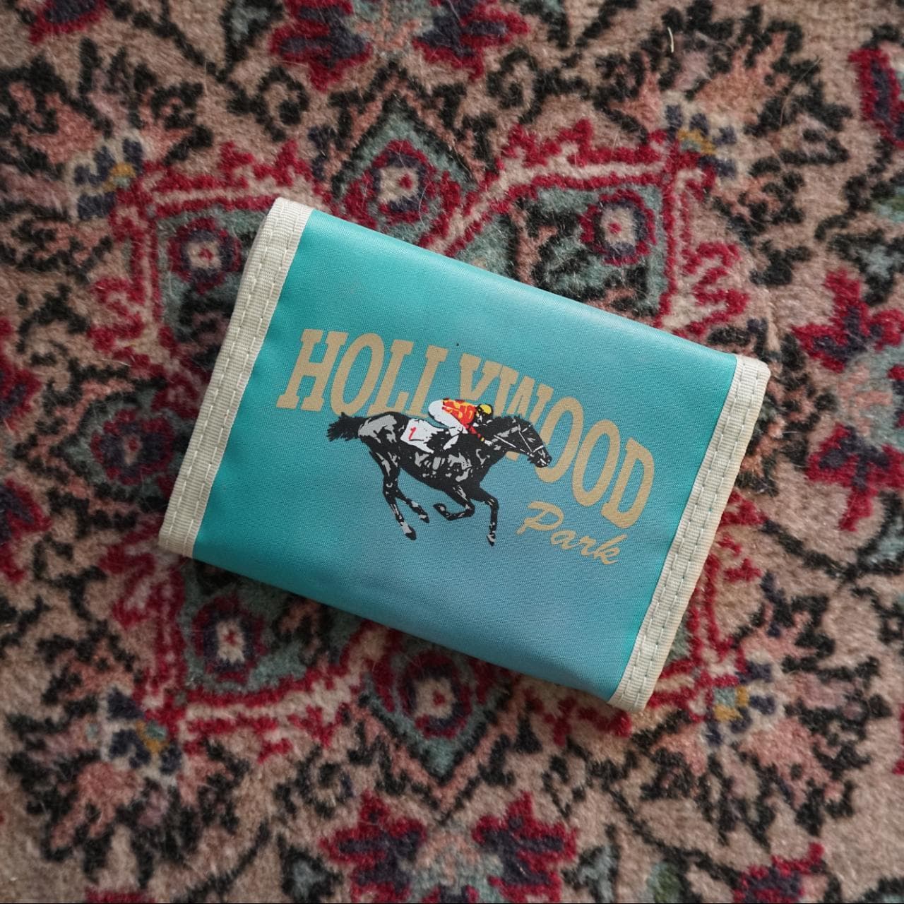 Teal and grey Hollywood Park vintage wallet. Screen print graphic on front. Features multiple pocket interior with coin pocket and a velcro closure. *Never been used.