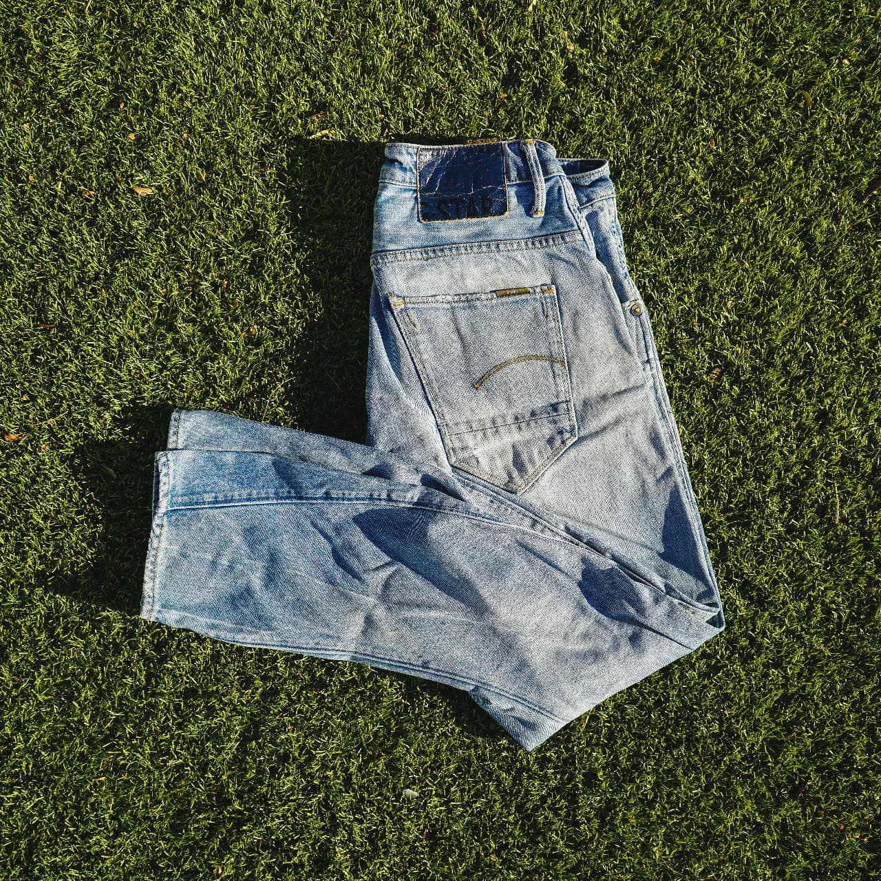 G-STAR Raw jeans in Men's Size 30. Features a light faded wash, with Japanese-style draped legs. Denim shows distress on the front, and back, and features G-STAR logo details throughout.