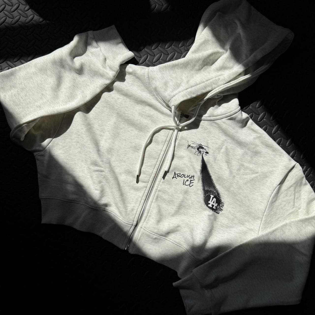Grey cropped zip up hoodie by Neon Gymnasium. Features metal tone zipper and accents with a graphic on the front and text on the back. Available in S-XXL. - Thumbnail 2