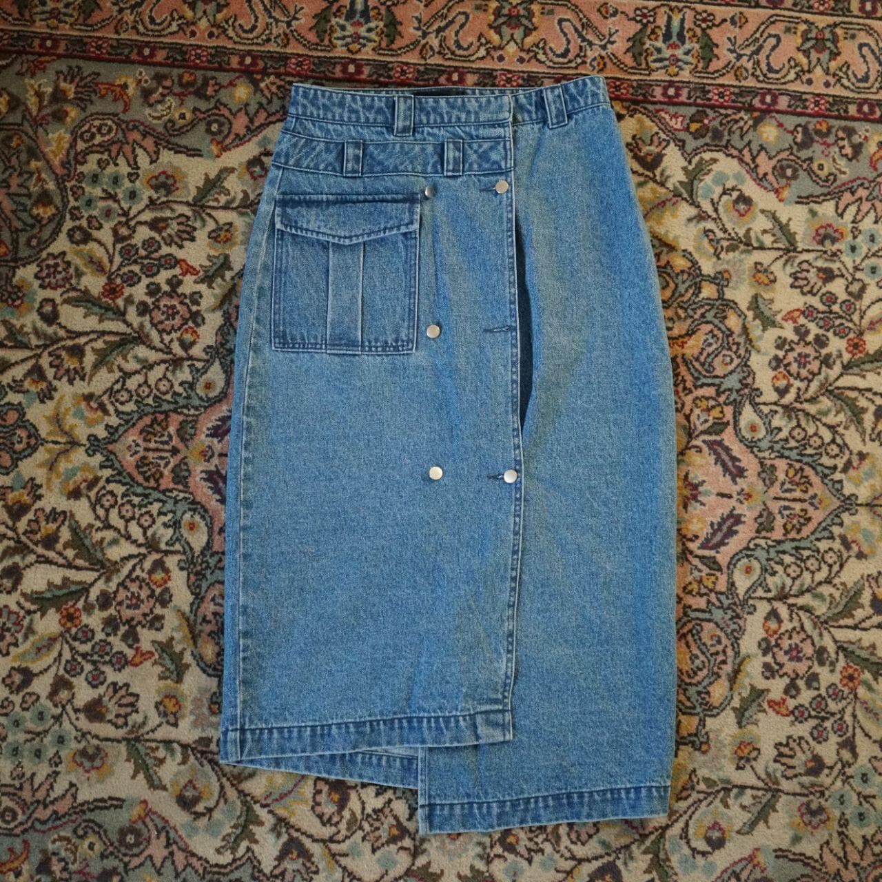 Very cute assymmetrical denim skirt in women's small. Features a front pocket, button closure, and asymmetric bottom.