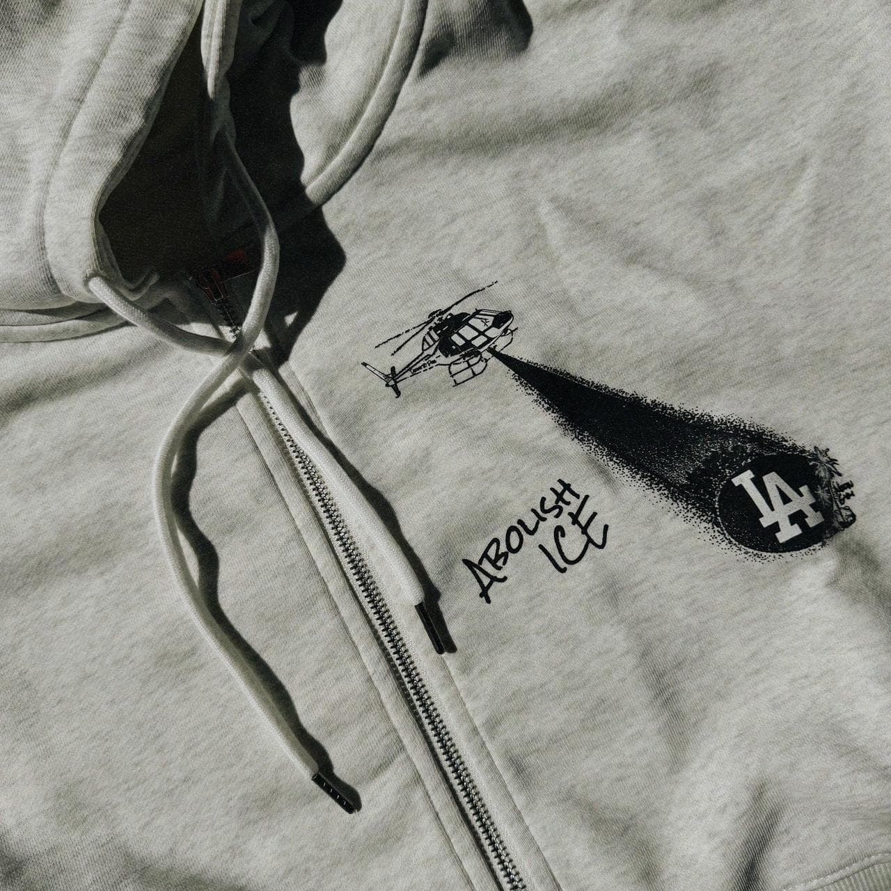 Grey cropped zip up hoodie by Neon Gymnasium. Features metal tone zipper and accents with a graphic on the front and text on the back. Available in S-XXL.