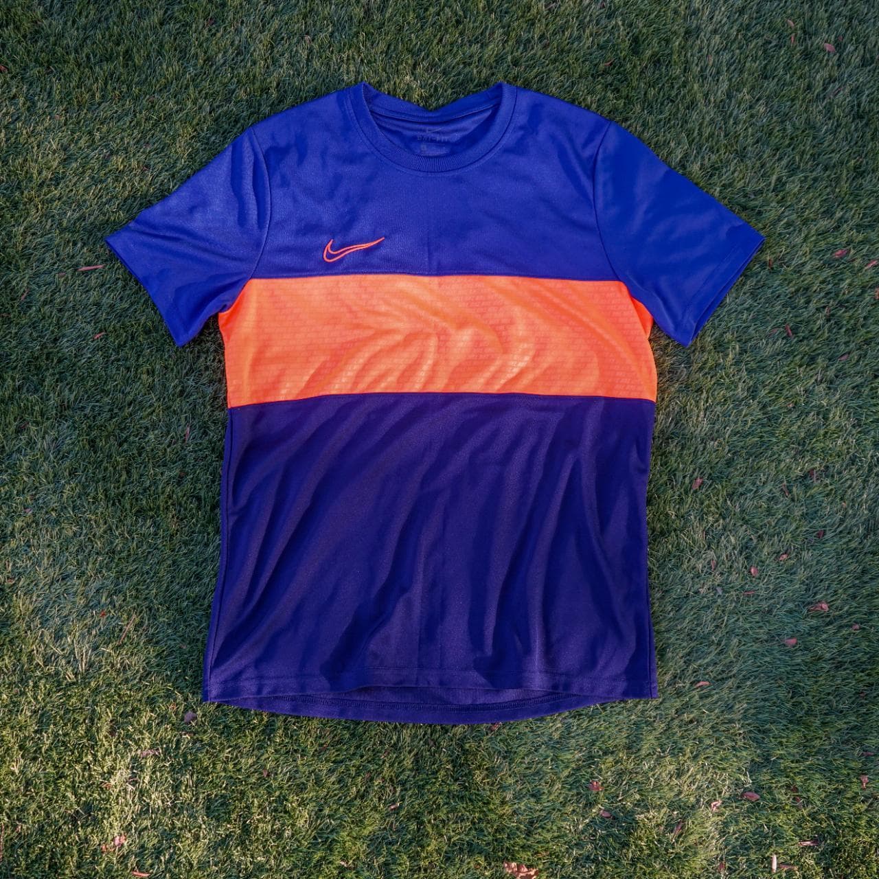 Nike soccer jersey in royal blue, navy, and highlighter orange. It features an embroidered logo, monogram print throughout, and dri-fit material. Size: adult large.