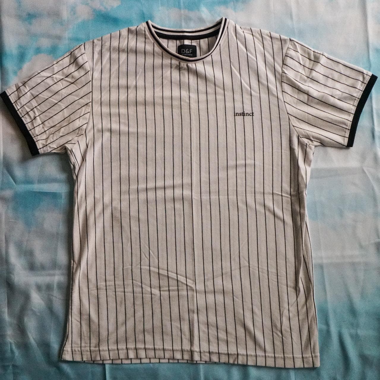 White and black pin striped shirt with a small "Instinct" logo on the front. Features contrast sleeve cuffs. Size adult small 👟