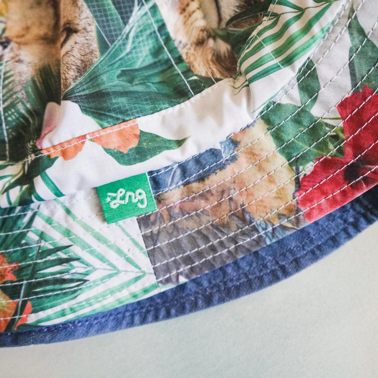 Crazy #LRG reversible bucket hat. Features medium-washed denim on one side with logo tag and full-color tropical print on the other side. The Y2K style is back and this accessory is perfect for the Summer 🌲 - Thumbnail 2