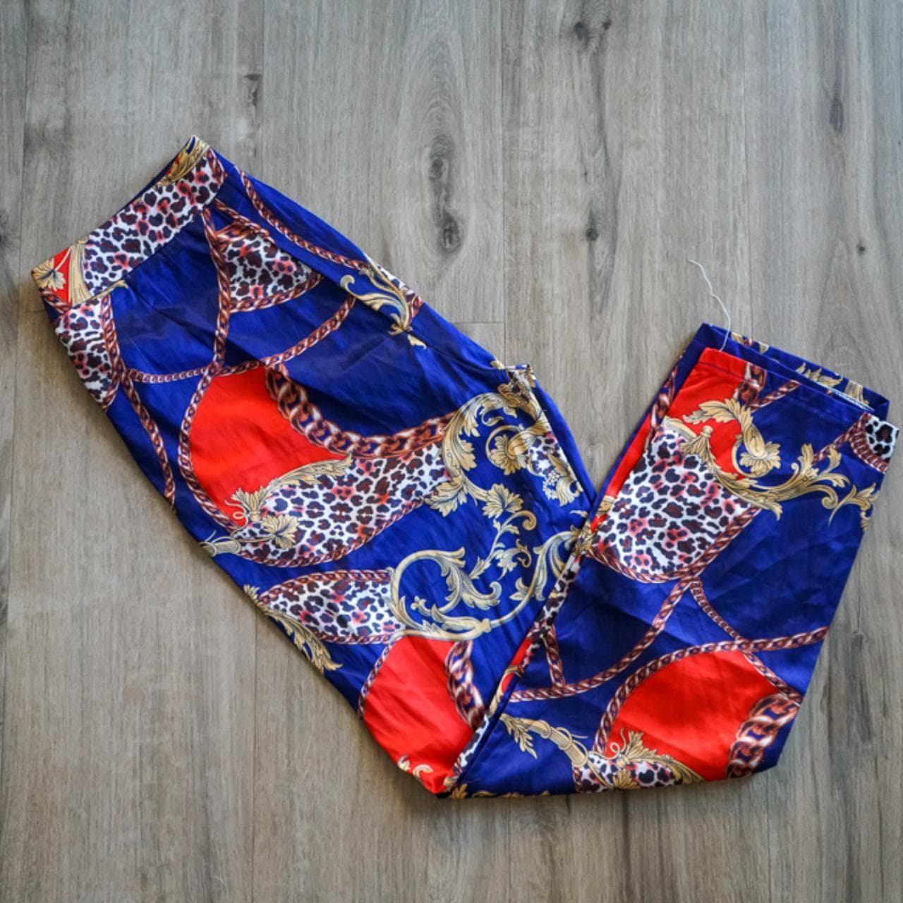 Patterned dress pants with side zipper closure. Blue, red, and animal print with chain accents. Tailored leg closure. Size women's small.