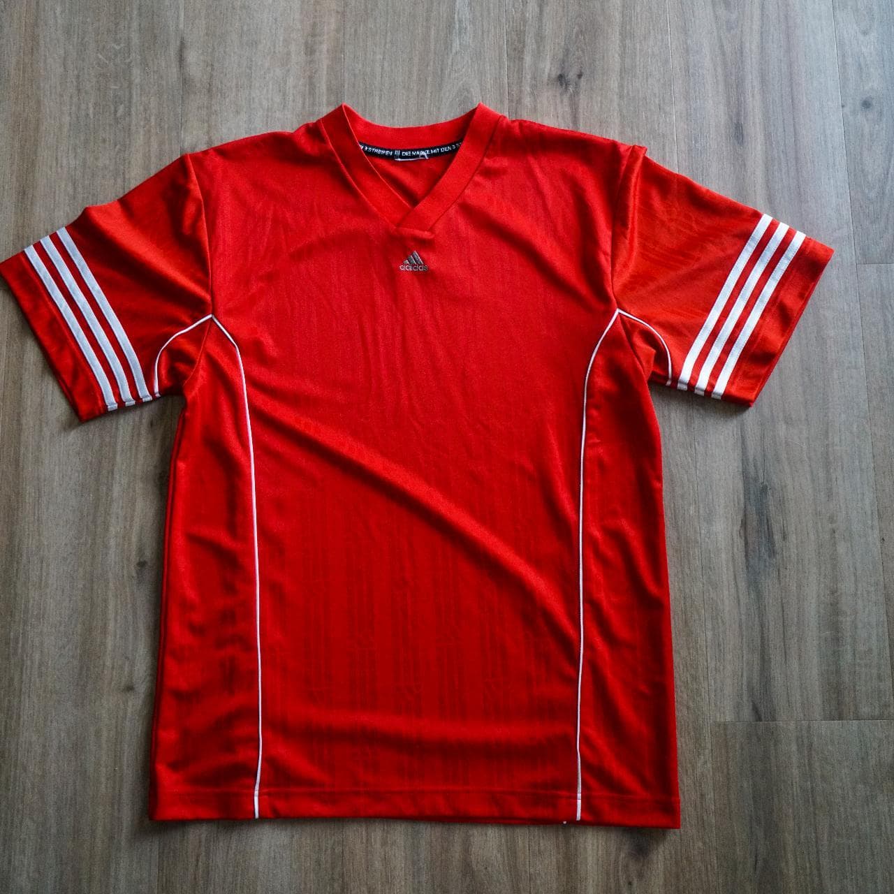 Vintage #Adidas soccer jersey in silky red ⚽️ Features 3-stripes on sleeves, white piping accents, Adidas logo in the middle, and repeating Adidas pattern throughout.
