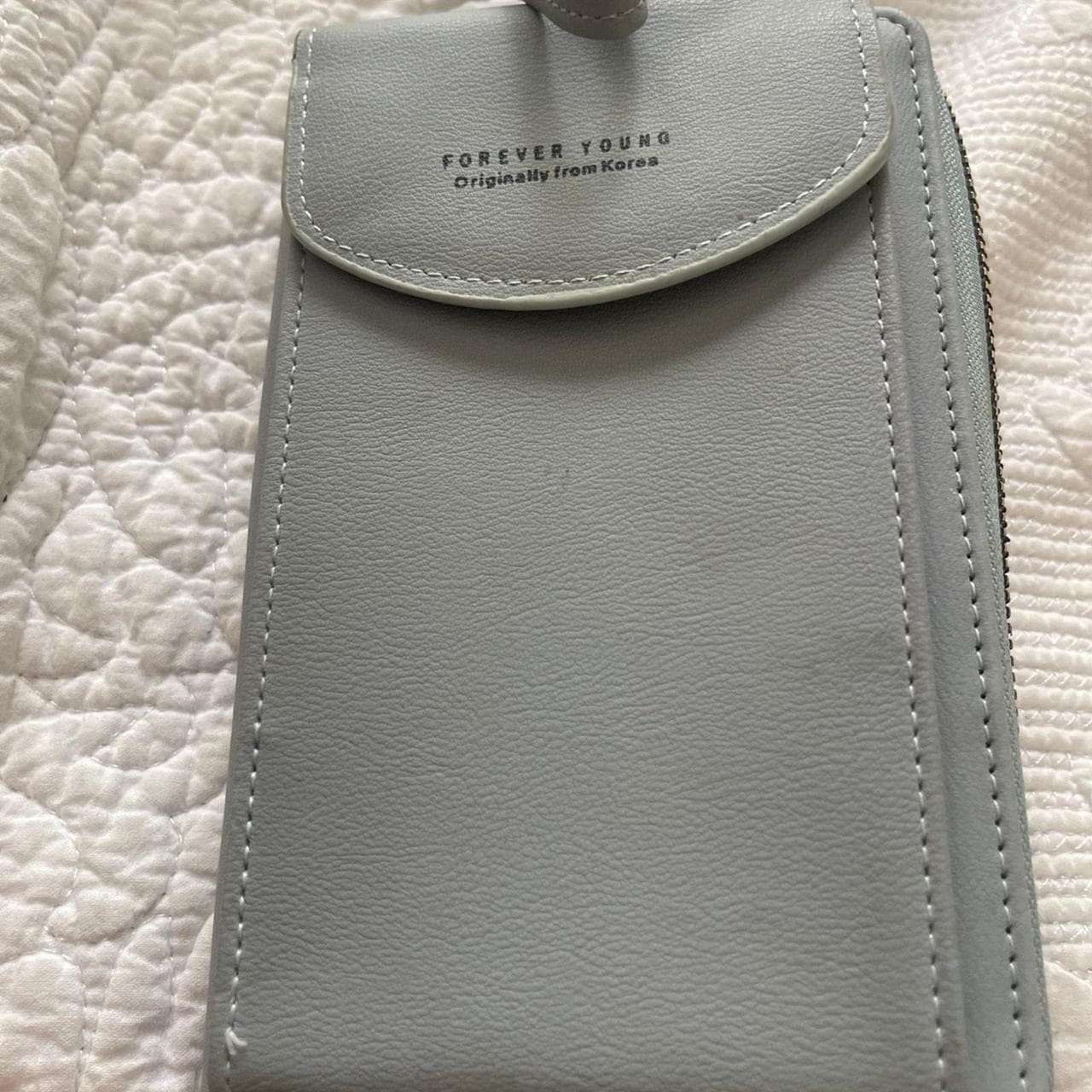 Keep your essentials organized in style with this Forever Young crossbody phone wallet. Designed in a soft light blue faux leather finish, this compact bag features a dedicated phone pocket, multiple card slots, cash compartments, and a secure zip-around wallet interior. The adjustable crossbody strap makes it perfect for errands, travel, concerts, or everyday use when you want to carry just the essentials. - Thumbnail 3