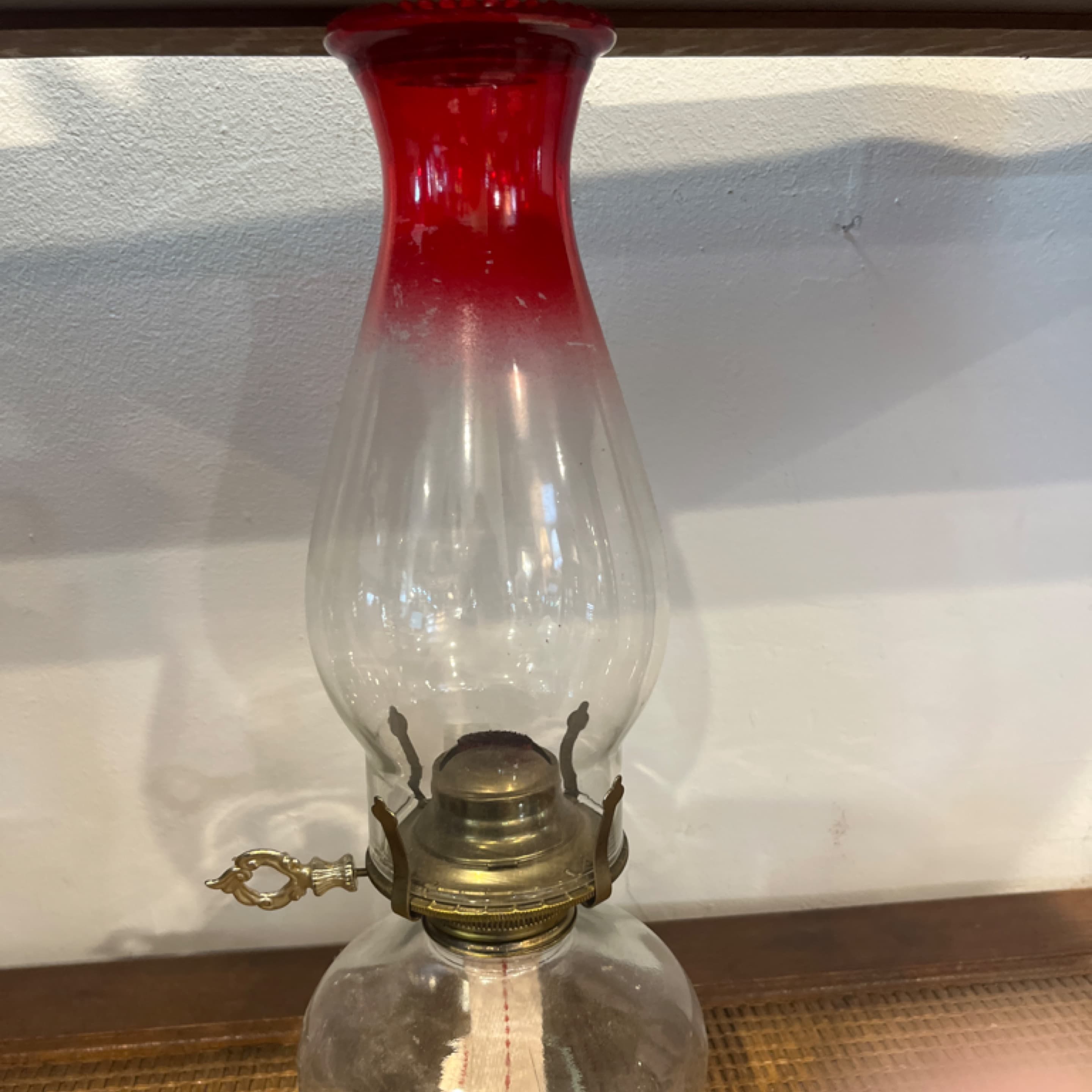 ruby red hurricane oil lamp features a clear glass base, a clear chimney with a ruby red top, and a brass burner. 941 - Regular