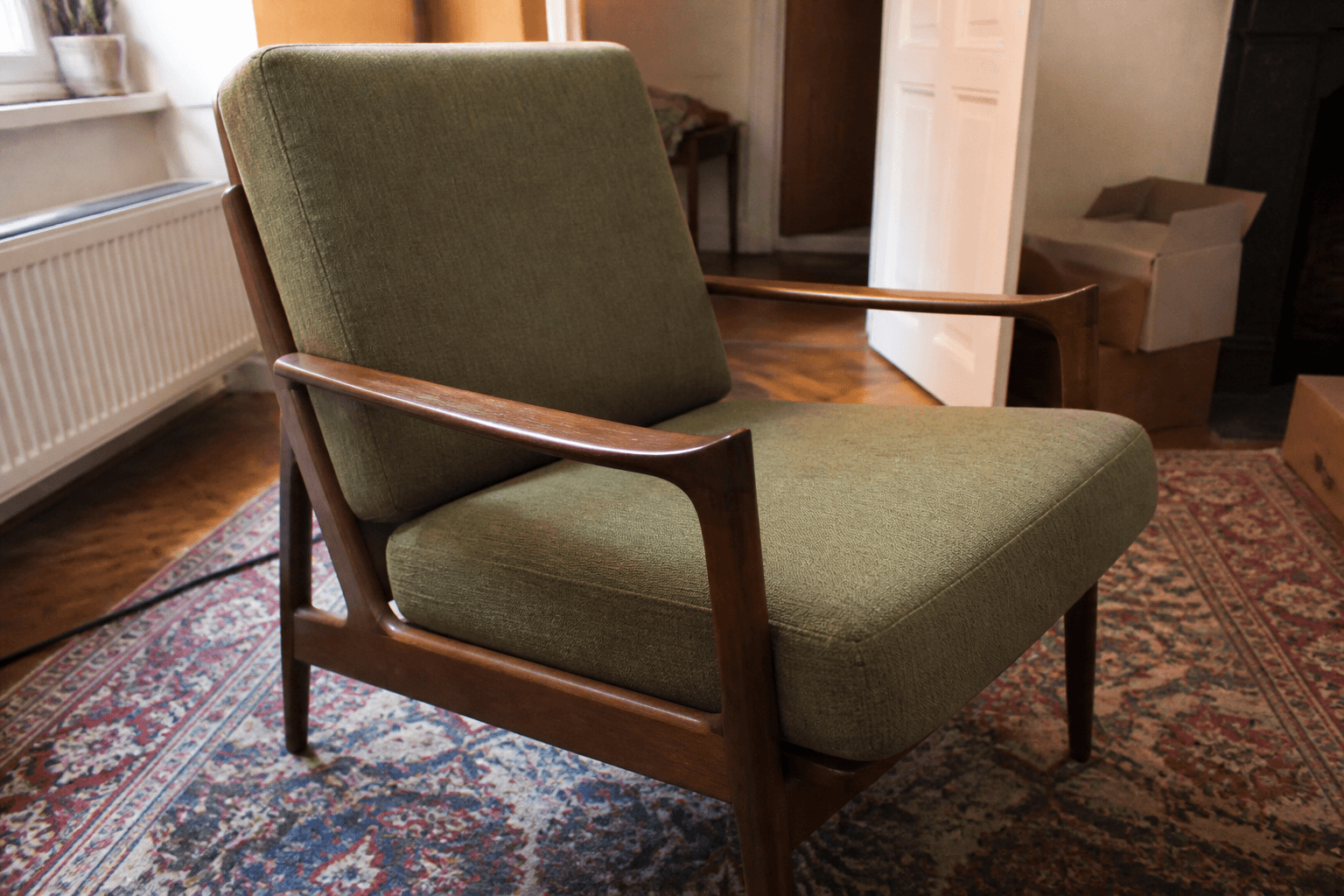 Armchair photographed in a cluttered room before editing