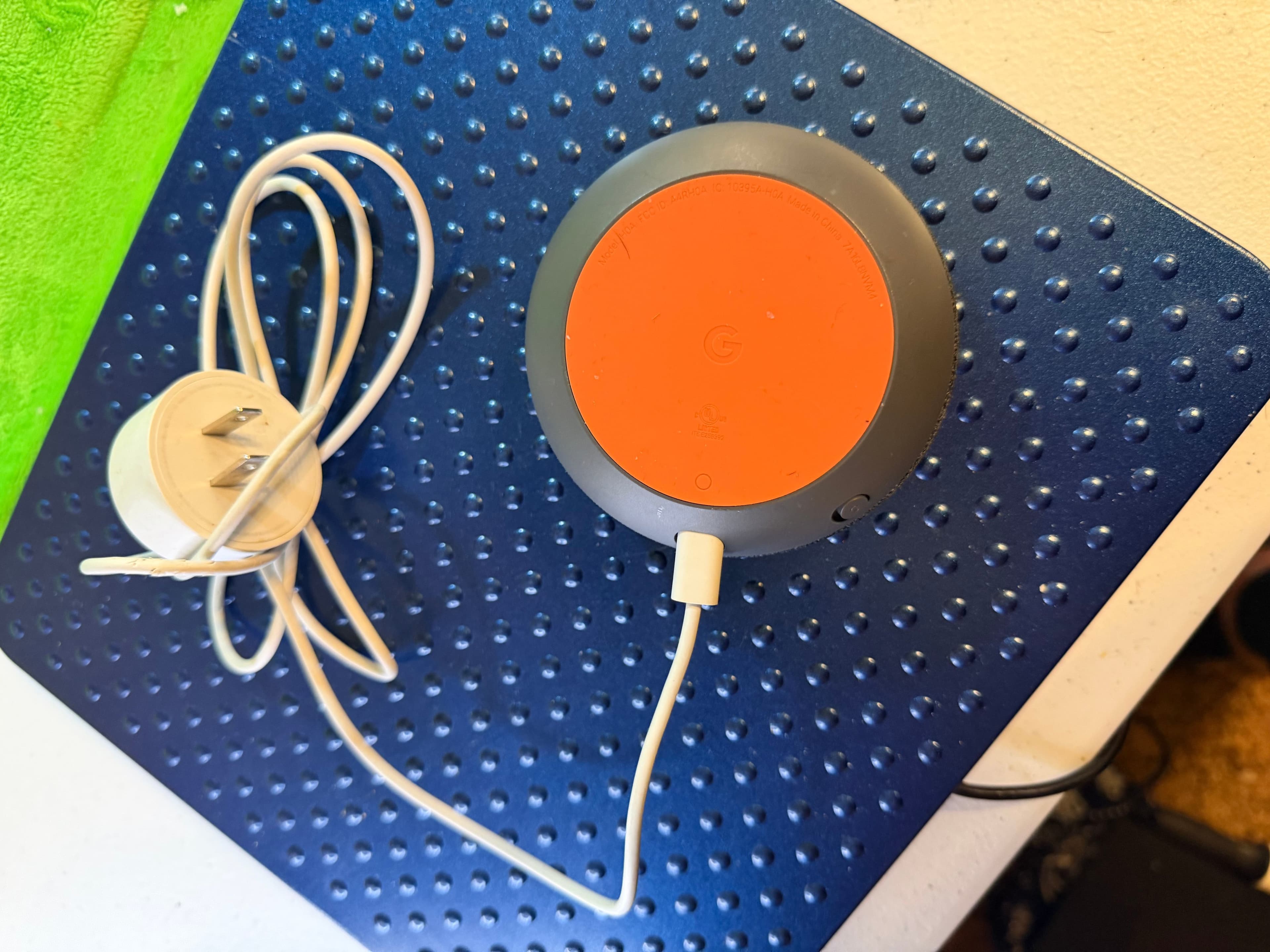 Google Home Mini smart assistant speaker in charcoal with an orange base