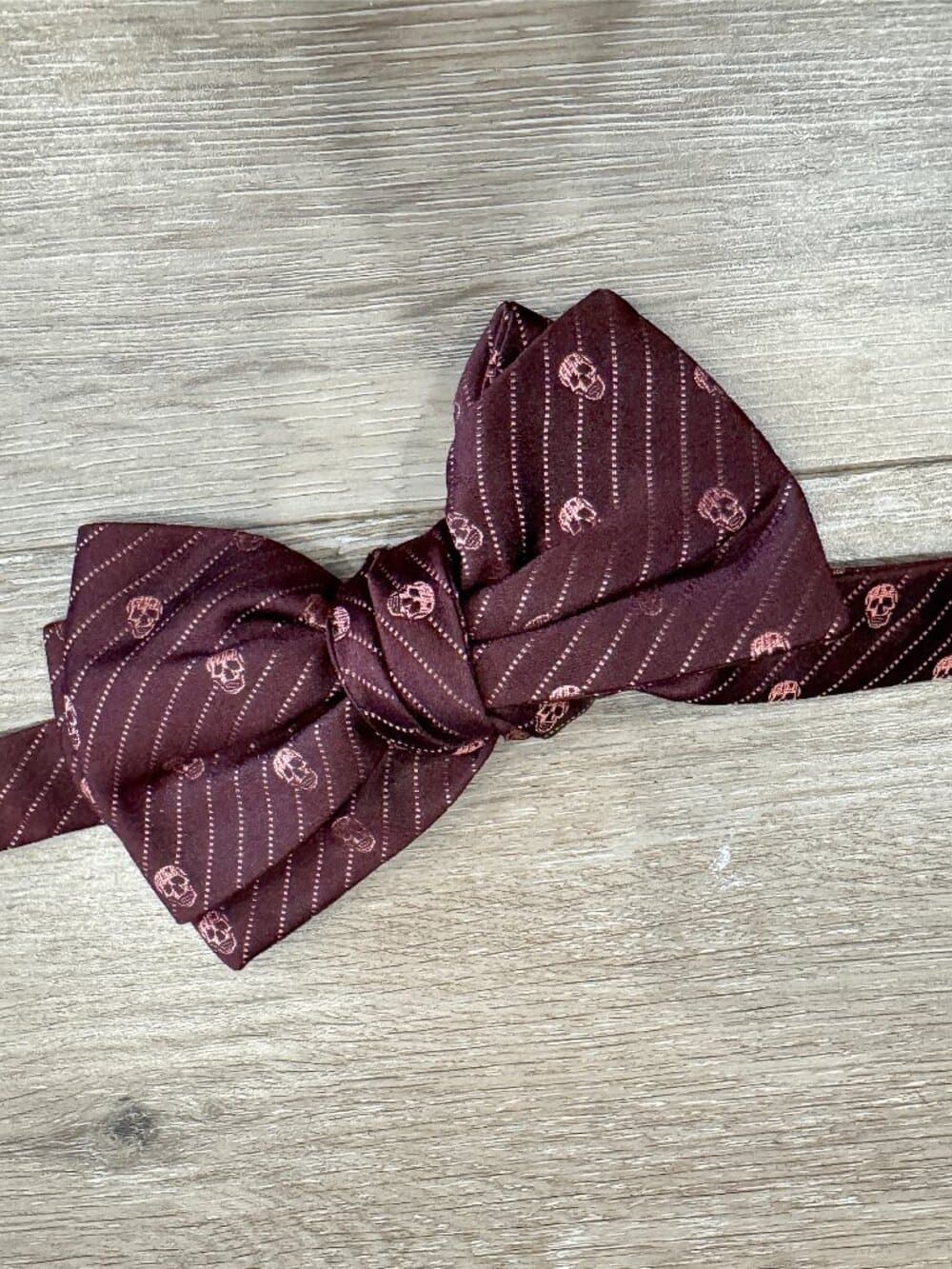 Alexander McQueen burgundy silk bow tie with a skull pattern.