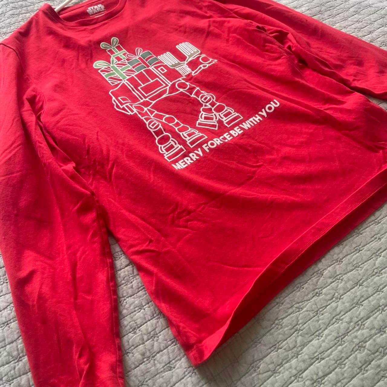 Celebrate the holidays with a galactic twist in this officially licensed Star Wars Christmas long sleeve T-shirt. Featuring an AT-AT Walker carrying a stack of Christmas presents and the festive phrase “Merry Force Be With You,” this bright red tee is perfect for Star Wars fans during the holiday season.