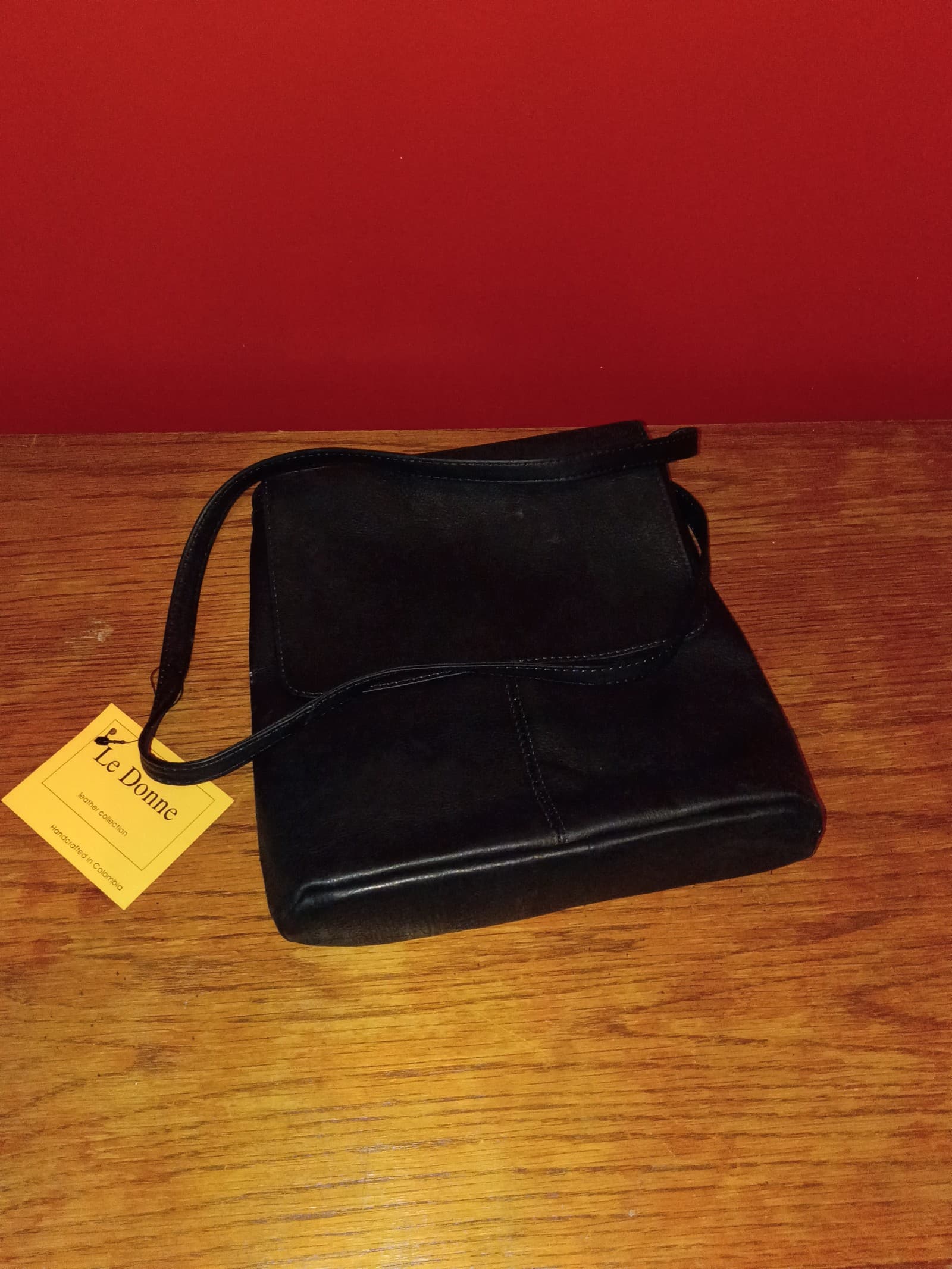 black Le Donne leather crossbody bag features a distinctive flap-over design.